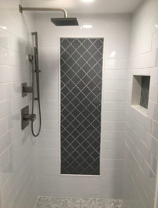 Remodeled walk-in shower with white subway tile, a gray arabesque accent panel and a built-in niche