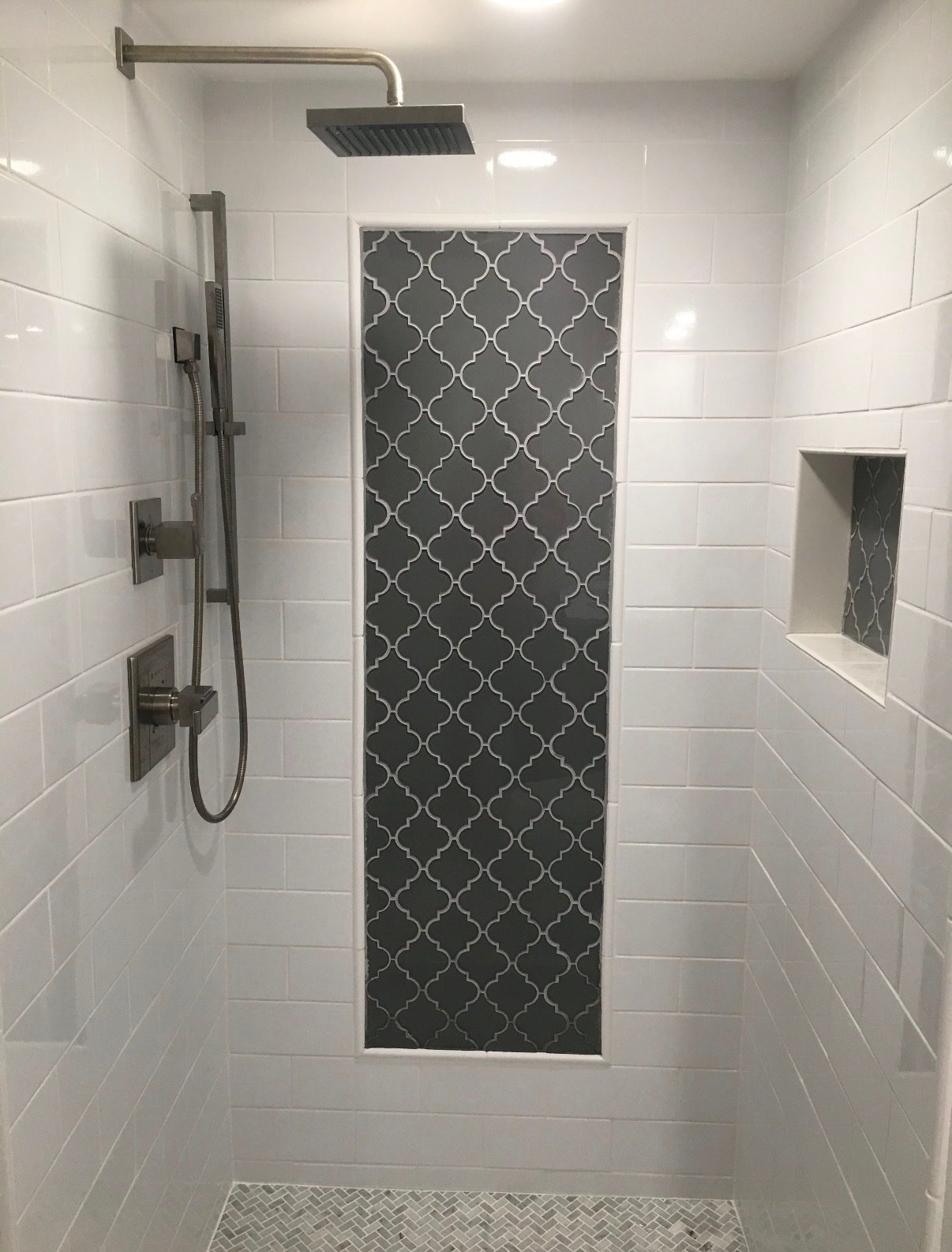 Remodeled walk-in shower with white subway tile, a gray arabesque accent panel and a built-in niche