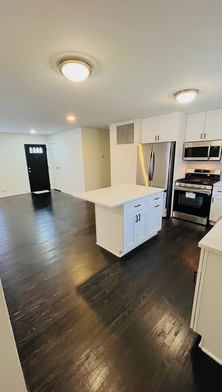 Dark stained hardwood floor refinished in an open kitchen and living area