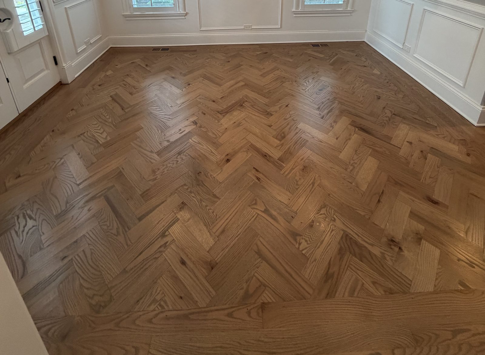 Herringbone hardwood flooring in a formal dining room with white wainscoting