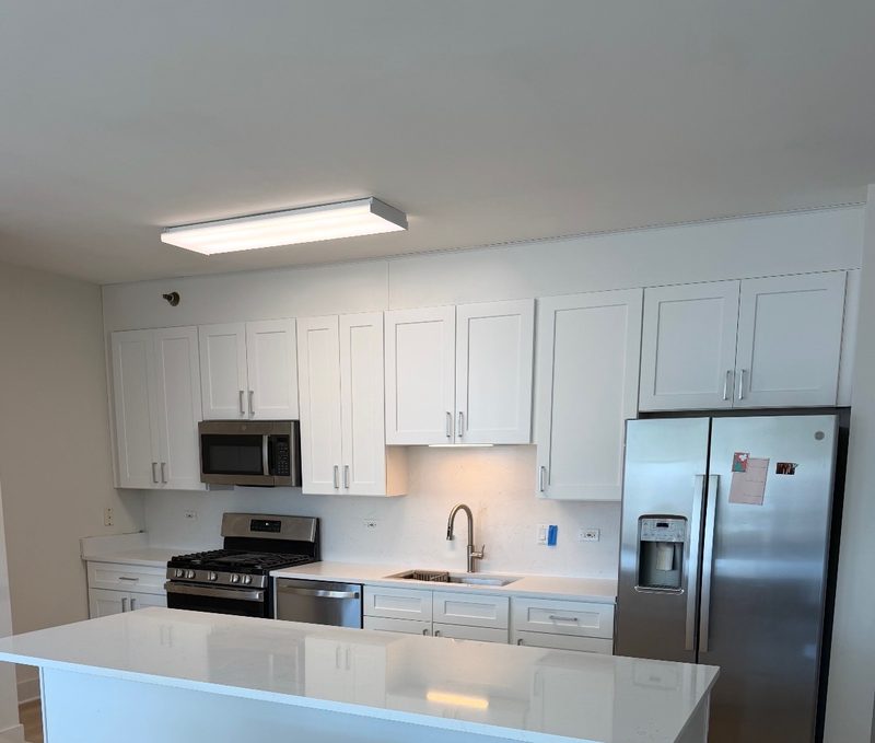 Open kitchen remodel with white shaker cabinets, quartz countertops and a large island