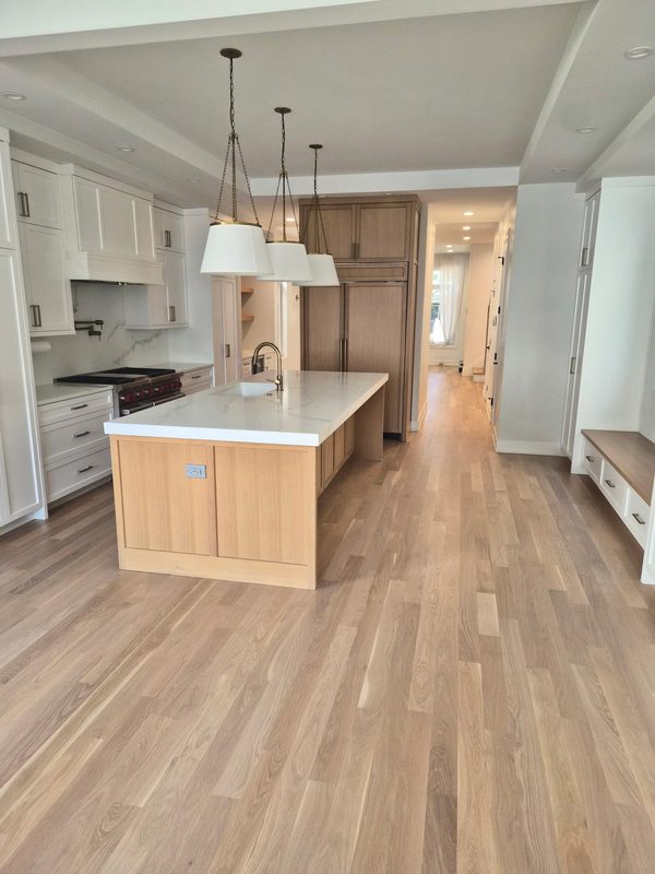 Wide-plank white oak hardwood flooring running through an open kitchen with a quartz-topped island